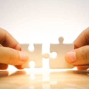 Two hands connecting puzzle pieces symbolizing seamless system integration